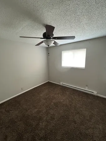 an empty room with a window and a fan