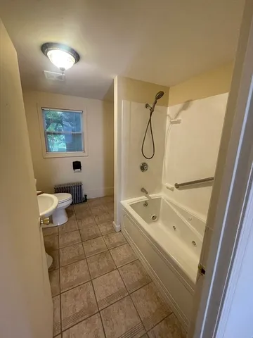 a bathroom with a tub a toilet and a shower