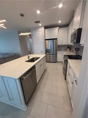 a kitchen with stainless steel appliances kitchen island granite countertop a sink and a refrigerator