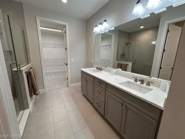 a spacious bathroom with a double vanity sink a mirror and a shower