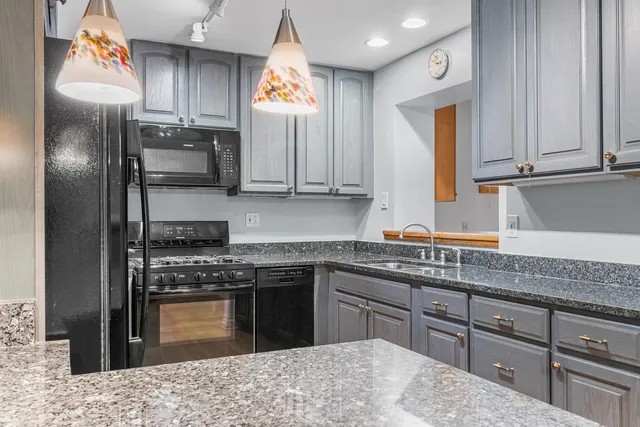 a kitchen with stainless steel appliances granite countertop a sink a stove a refrigerator cabinets and a window