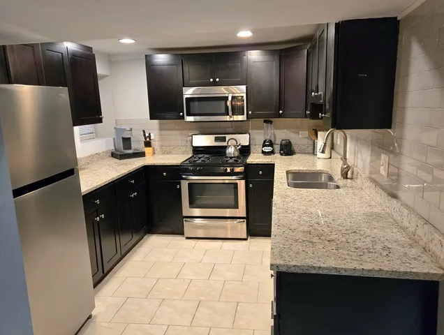 a kitchen with stainless steel appliances granite countertop a sink stove and refrigerator