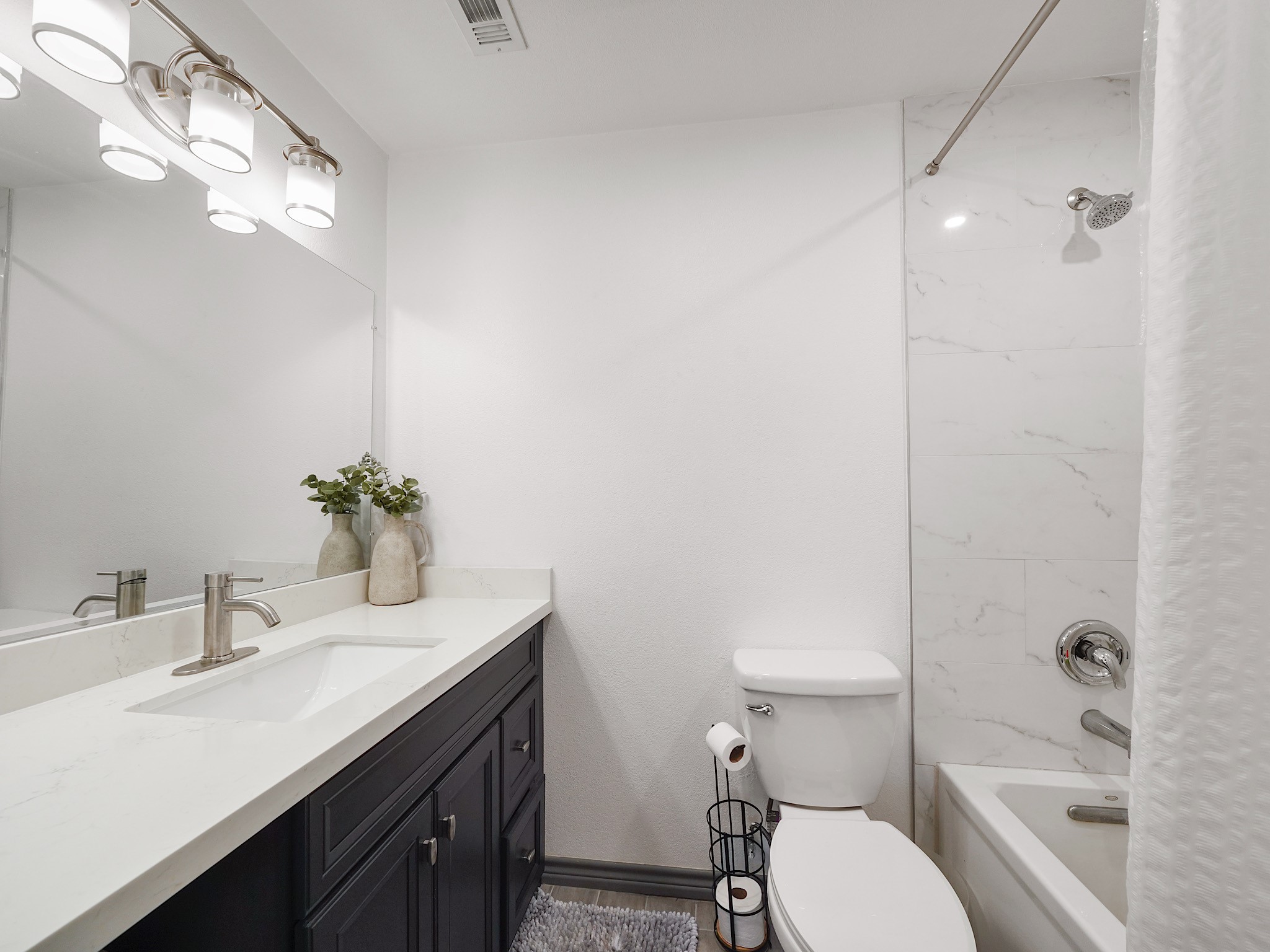 9616 Long Point Road, Unit 47 Houston, TX 77055 - Photo 13 of 15 Classic tile surrounds the tub-shower combination, paired with a vanity that sits beneath bright lighting—simple, clean, and ready for daily routines.