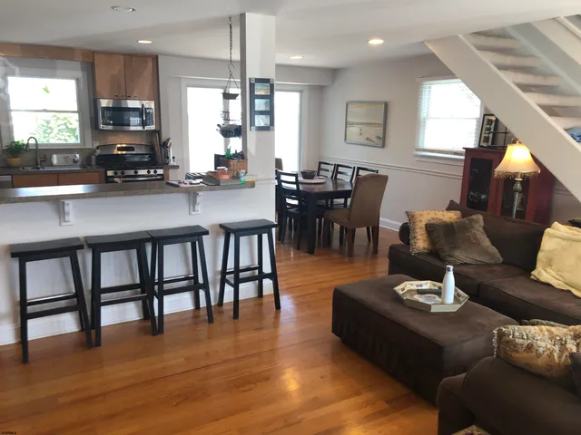 a living room with furniture kitchen view and a wooden floor