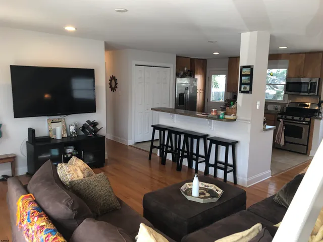 a living room with furniture a flat screen tv and kitchen view