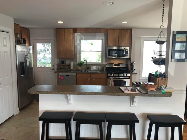 a kitchen with stainless steel appliances granite countertop a dining table chairs refrigerator and sink