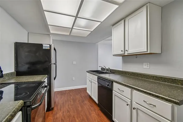 a kitchen with granite countertop a sink appliances and cabinets