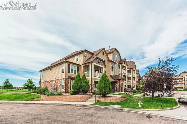a front view of a building with garden and trees