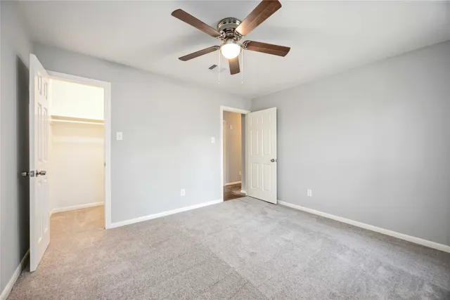 an empty room with closet and a ceiling fan