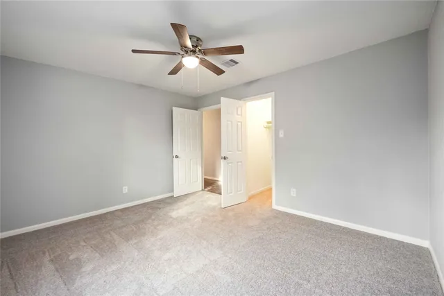 a view of an empty room and chandelier fan