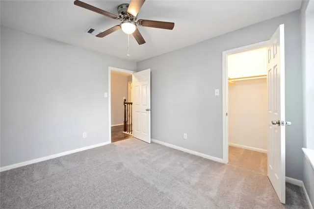 an empty room with closet and a chandelier fan