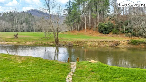 a view of a lake with a yard and large trees