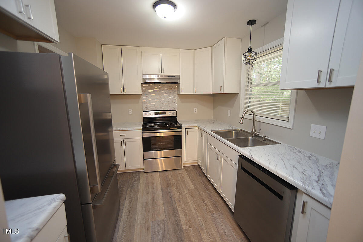 8009 Boxer Place Wake Forest, NC 27587 - Photo 5 of 11 a kitchen with stainless steel appliances granite countertop a refrigerator a sink dishwasher a stove and white countertops with wooden floor