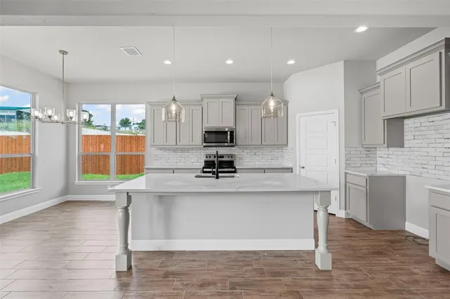 a kitchen with stainless steel appliances kitchen island granite countertop a stove and a sink