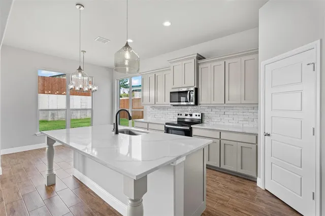 a kitchen with kitchen island granite countertop a sink a counter space appliances and cabinets