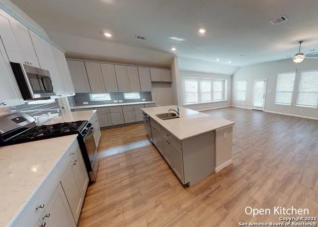 a kitchen with a refrigerator a sink a stove a microwave and wooden floor