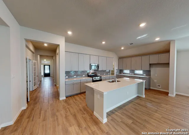 a large kitchen with a large counter top a sink stainless steel appliances and cabinets