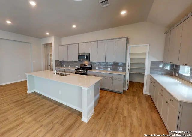 a kitchen with kitchen island a sink a stove a refrigerator and white cabinets