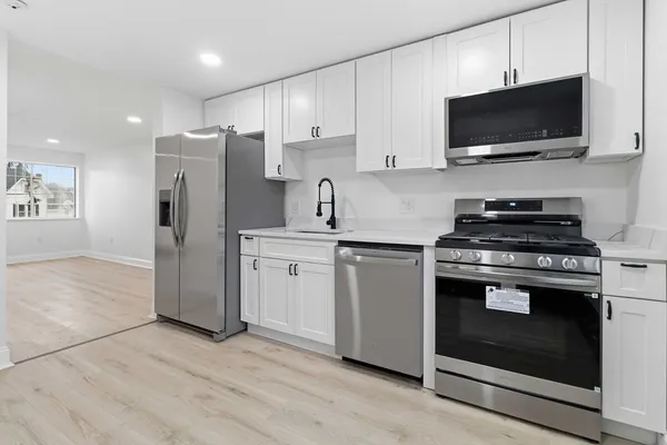 a kitchen with stainless steel appliances a refrigerator stove and white cabinets