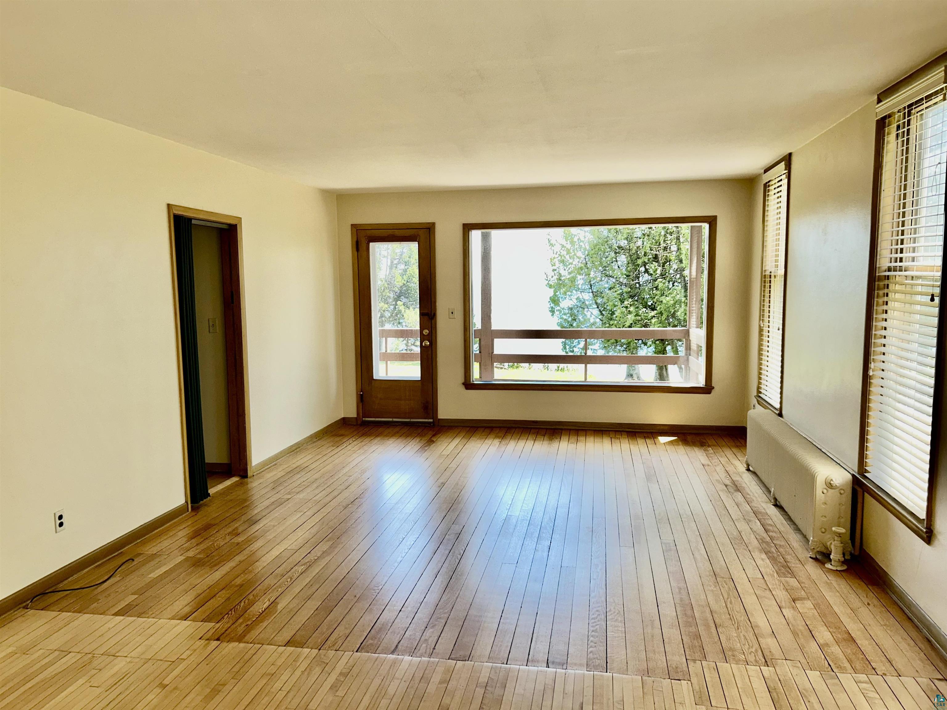 5090 London Road, Unit 1 Duluth, MN 55804 - Photo 14 of 54 Bright room featuring wood-finish flooring, a large picture window, and an exterior door with glass paneling