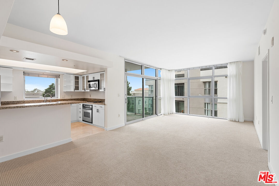 13700 Marina Pointe Drive, Unit 517 Marina del Rey, CA 90292 - Photo 1 of 54 a large white kitchen with granite countertop a large window and a sink