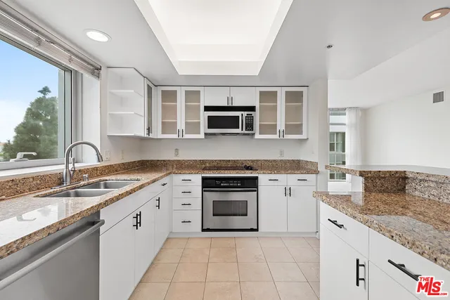 a kitchen with granite countertop a sink stove and cabinets
