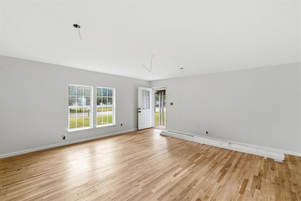 203 North Kickapoo Street Lipan, TX 76462 - Photo 7 of 28 an empty room with wooden floor and windows