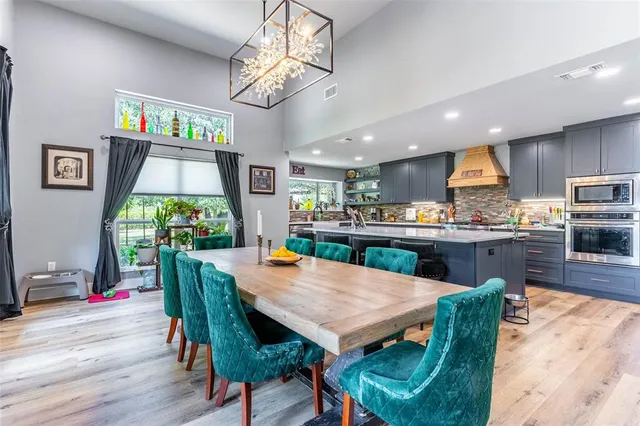 a kitchen with stainless steel appliances granite countertop table chairs sink and wooden floor