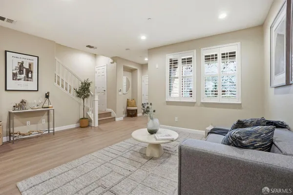 a living room with furniture a wooden floor and next to a window