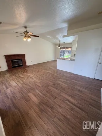 an empty room with wooden floor chandelier fan and windows