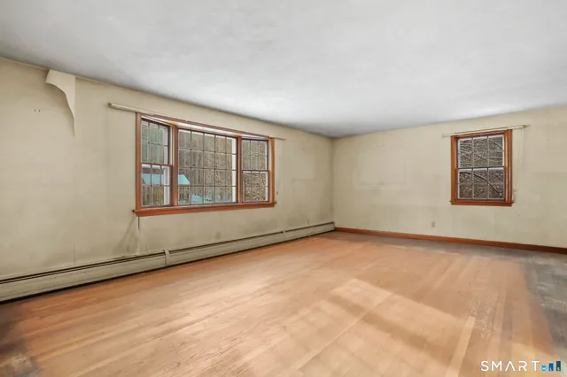 an empty room with wooden floor and mirror