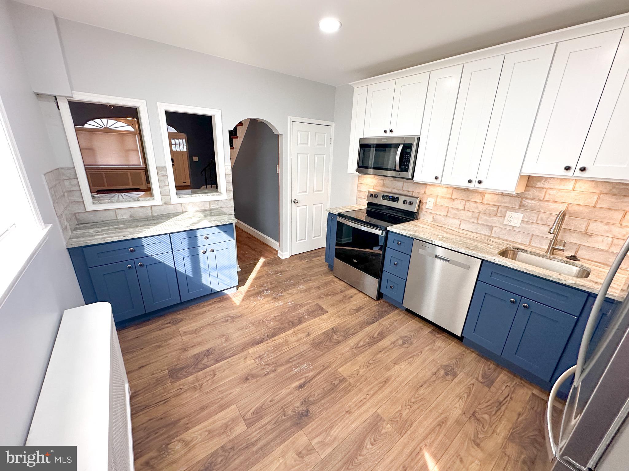 a kitchen with stainless steel appliances granite countertop a stove a sink dishwasher a microwave oven and a refrigerator with wooden floor