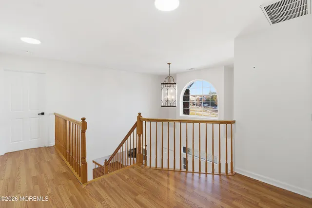 a view of a hallway with wooden floor and staircase
