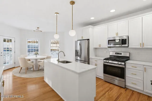 a kitchen with stainless steel appliances a stove a sink a microwave a dining table and chairs