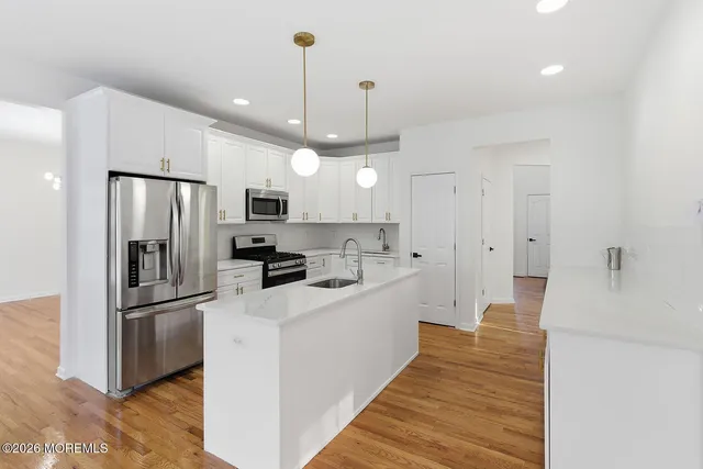 a large kitchen with a sink stainless steel appliances and cabinets