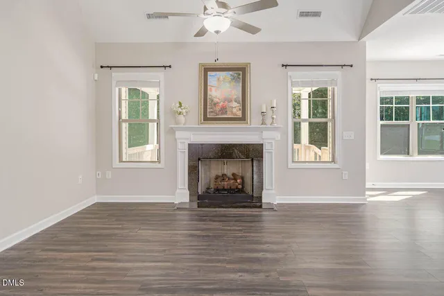 an empty room with wooden floor a fireplace and windows