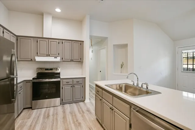 a kitchen with a sink cabinets stainless steel appliances and a window