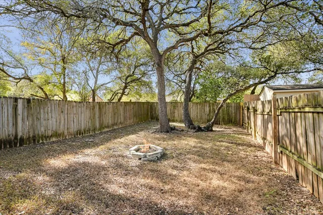 a backyard of a house with large trees and wooden fence