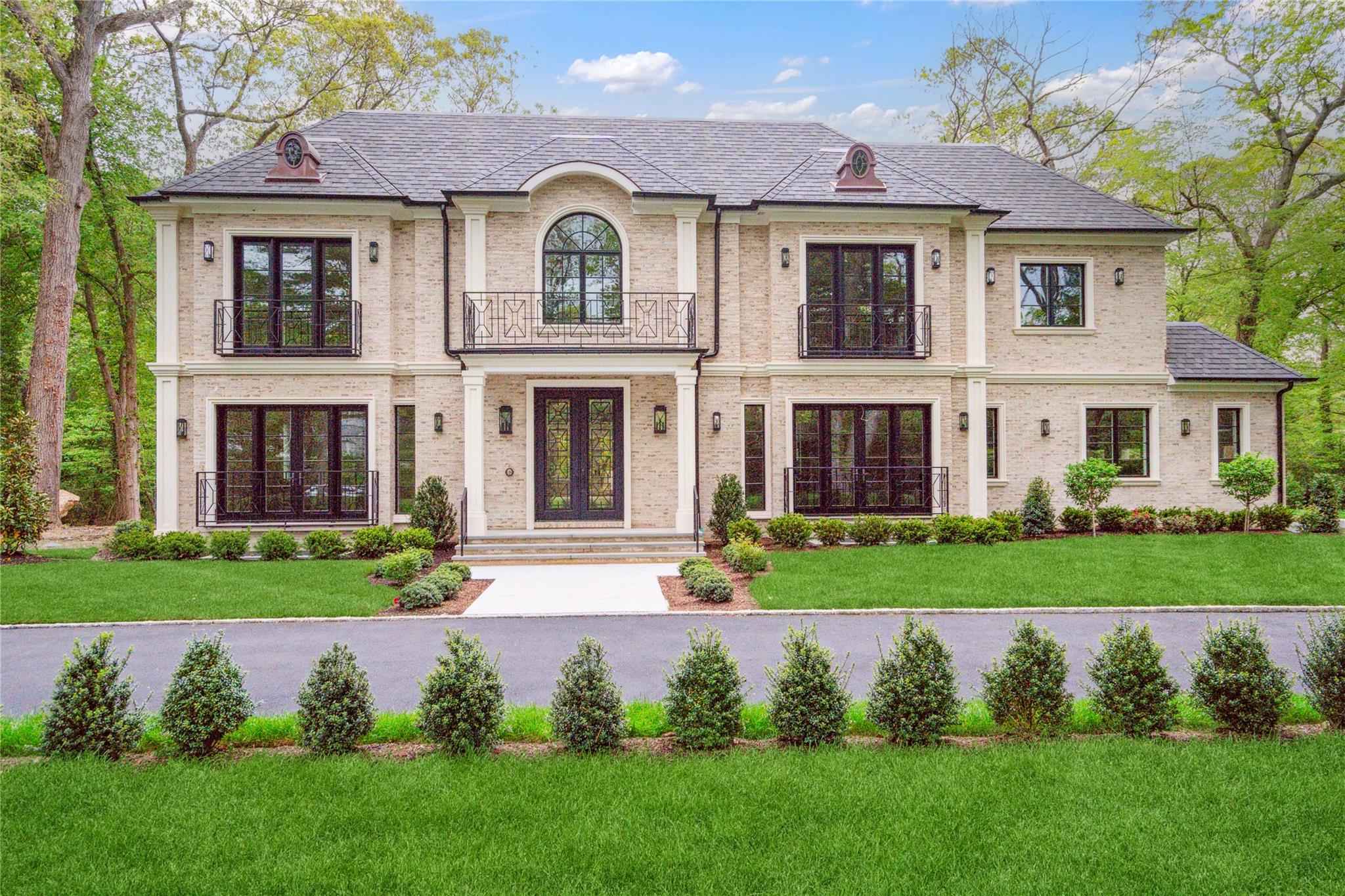 French country inspired facade with french doors, a balcony, a front yard, and brick siding