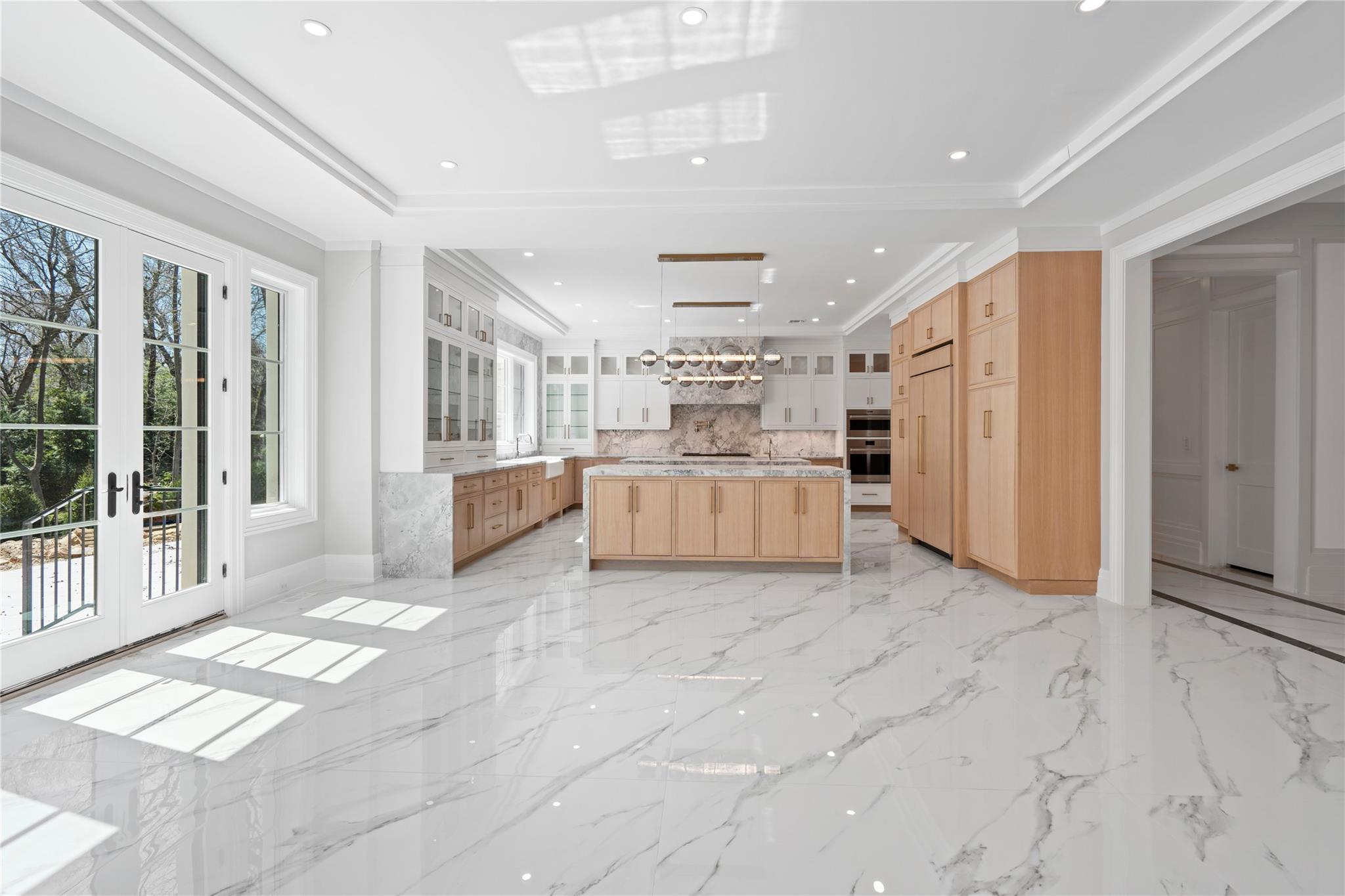 20 Knollwood Road Muttontown, NY 11545 - Photo 14 of 41 Kitchen featuring light brown cabinets, glass insert cabinets, light countertops, backsplash, and a spacious island