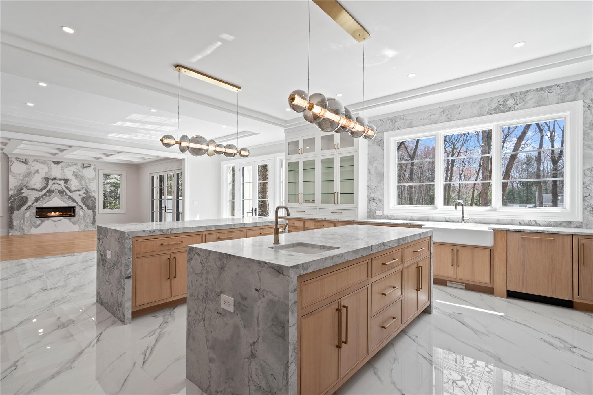 20 Knollwood Road Muttontown, NY 11545 - Photo 18 of 41 Kitchen featuring light stone countertops, light brown cabinets, a large island, and a sink