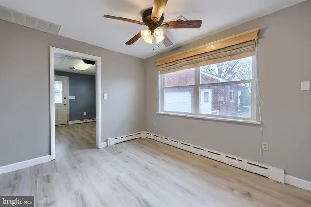 a view of an empty room with a window and wooden floor