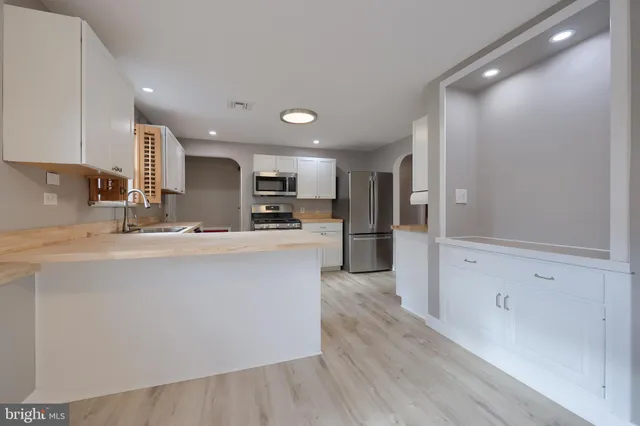 a kitchen with stainless steel appliances kitchen island granite countertop a refrigerator a sink a stove and oven with wooden floor