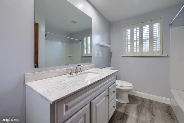 a bathroom with a granite countertop toilet sink and mirror