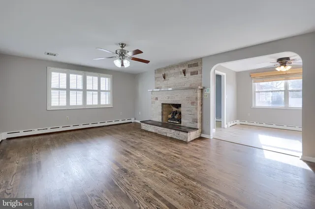 an empty room with wooden floor fireplace and windows