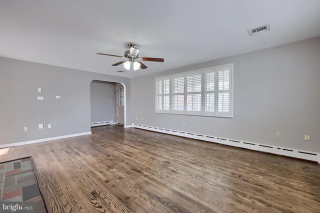 a view of an empty room with a window and wooden floor