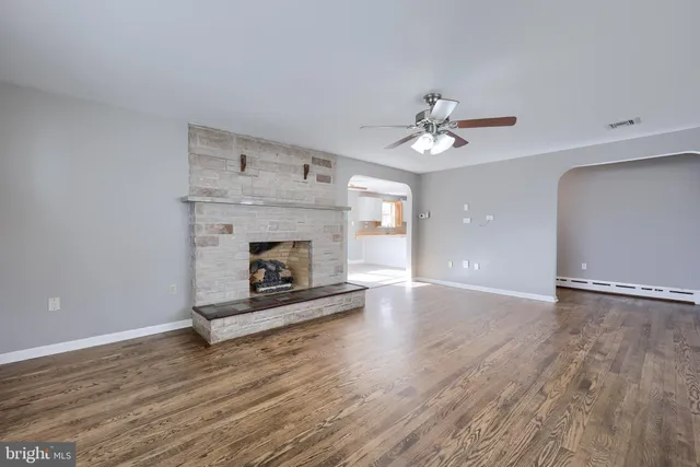a view of an empty room with wooden floor a fireplace and a window