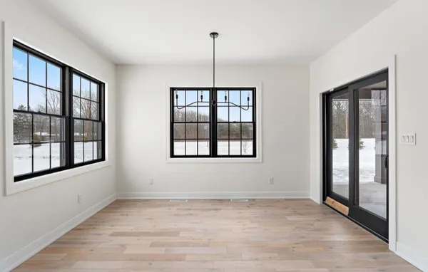 an empty room with wooden floor chandelier fan and windows