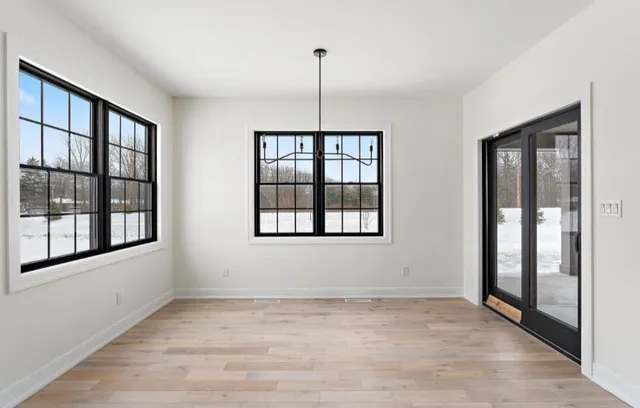 an empty room with wooden floor chandelier fan and windows