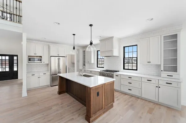 a large white kitchen with a stove a sink dishwasher and a refrigerator with wooden floor